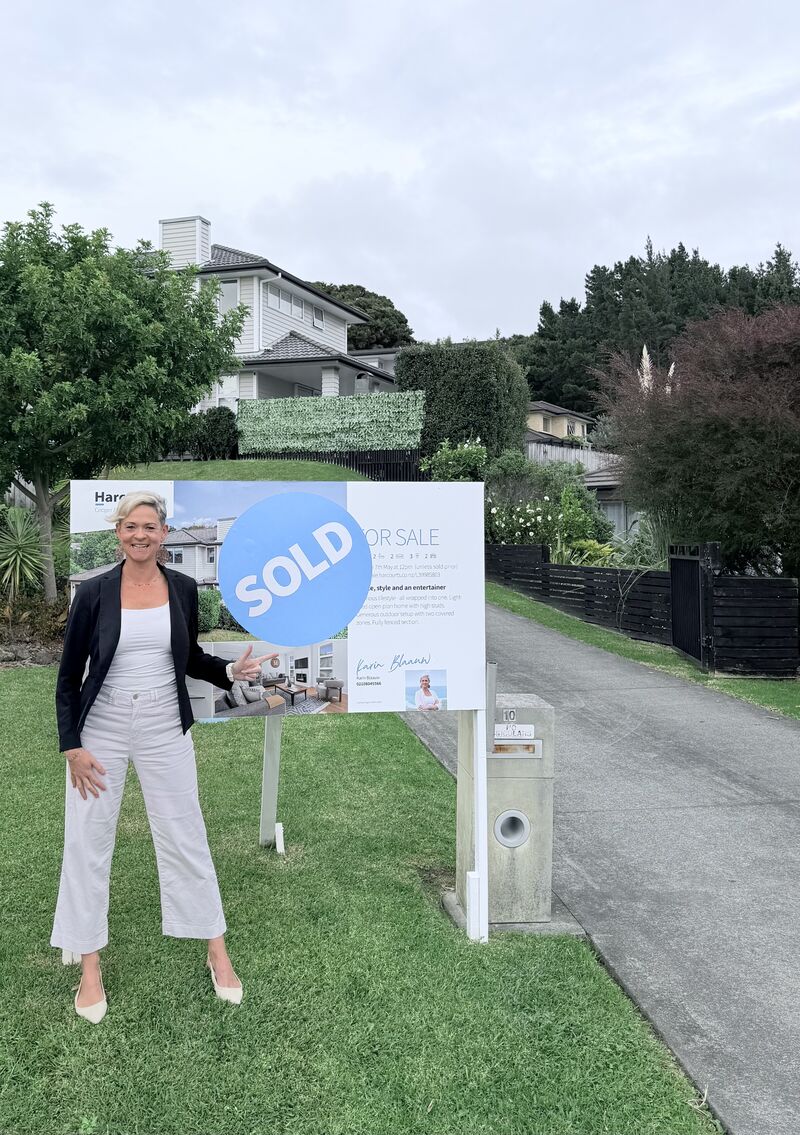 Karin Blaauw with the sold sign at 10 Bloomfield Rise, Stanmore Bay